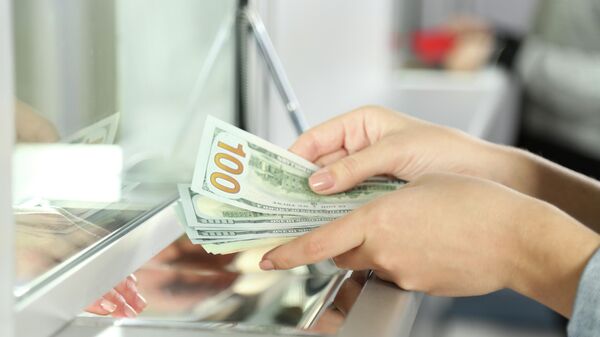 Женщина пересчитывает долларовые купюры в банке  