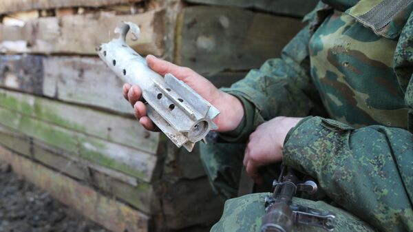 Военнослужащий ДНР демонстрирует осколок снаряда, которыми обстреливают их позиции