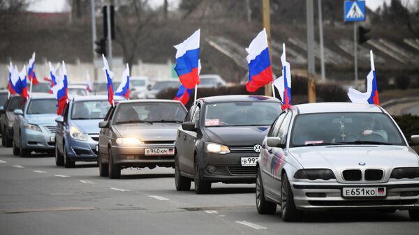 Люди едут на машинах с флагами России по улице Донецка