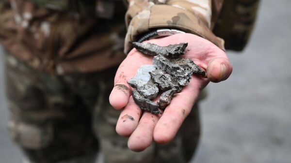 Военнослужащий демонстрирует осколки боеприпасов в Донецке после обстрела