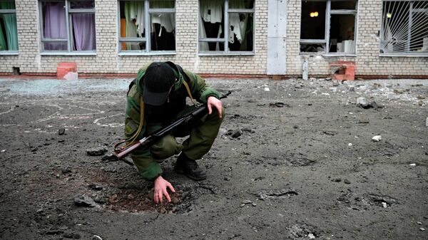 Сотрудник народной милиции ДНР возле воронки от снаряда у школы Горловки