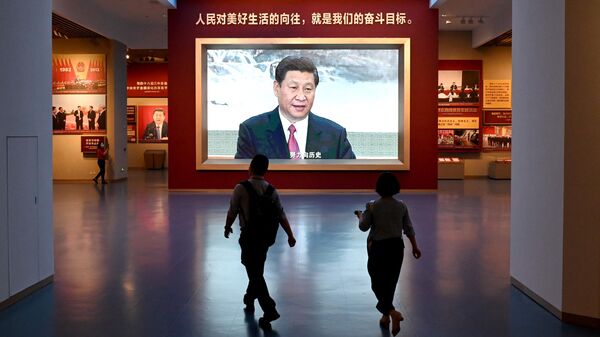Журналисты проходят мимо экрана с изображением президента Китая Си Цзиньпина во время посещения Музея Коммунистической партии Китая
