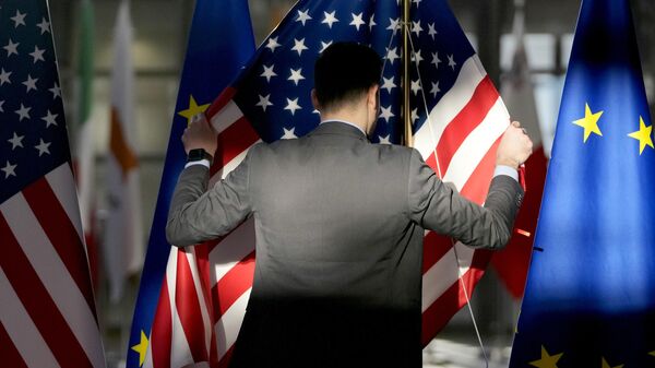 Сотрудник поправляет флаги США и ЕС