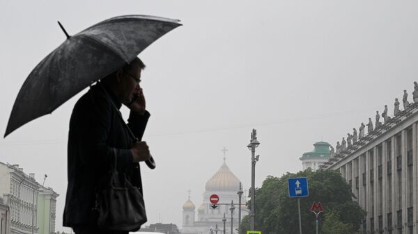 Мужчина с зонтом в дождливую погоду на одной из улиц в Москве