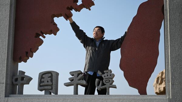 Мужчина возле скульптуры, изображающей Тайвань и материковый Китай, на острове Пинтань, КНР