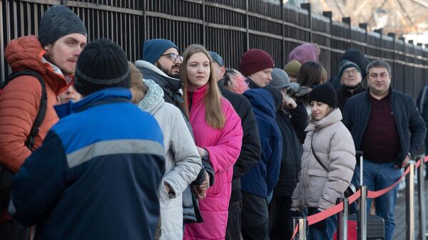 Люди стоят в очереди, чтобы проголосовать на выборах президента России на избирательном участке в посольстве России в Алма-Ате