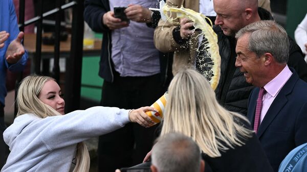 Девушка обливает молочным коктейлем лидера британской партии Reform UK Найджела Фараджа 