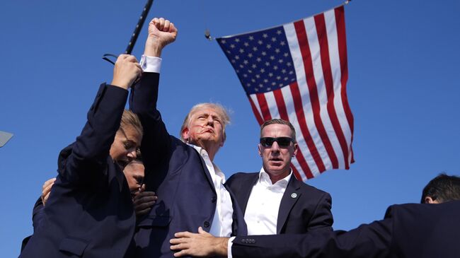Кандидата в президенты США от республиканской партии Дональда Трампа прикрывают агенты Секретной службы США на предвыборном митинге