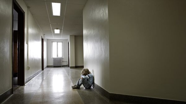 Расстроенный ребенок в пустом школьном коридоре 