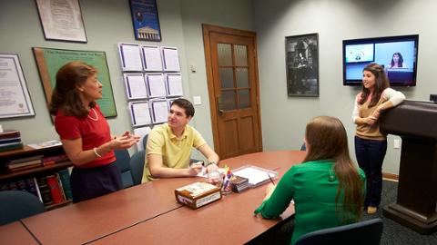 A professor and three students working together on a speech writing assignment.