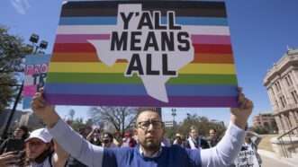 Person protesting in Texas with rainbow striped sign that says "Y'all means All" | Bob Daemmrich/ZUMAPRESS/Newscom