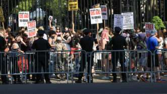 Police officers stand on the other side of a line of barricades from a crowd of protesters at Columbia University. | Luiz C. Ribeiro/TNS/Newscom