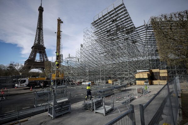 FILE - Workers build the stands for the upcoming Olympic Games on the Champ-de-Mars just beside the Eiffel Tower, in Paris, April 1, 2024 in Paris. (AP Photo/Thomas Padilla, File)