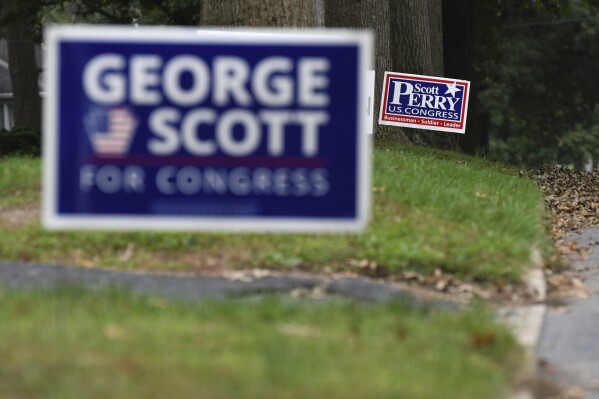 FILE - Campaign signs for Republican U.S. Rep. Scott Perry of Pennsylvania and Democratic challenger George Scott as seen on a neighbourhood street in the district, Saturday, Oct. 6, 2018 in Camp Hill, Pa. A federal appeals court panel has found that a small Pennsylvania town's ordinance designed to cut down on lawn signs is unconstitutional, saying that its resulting limitations on political lawn signs violates the free speech rights of residents. (AP Photo/Marc Levy, File)