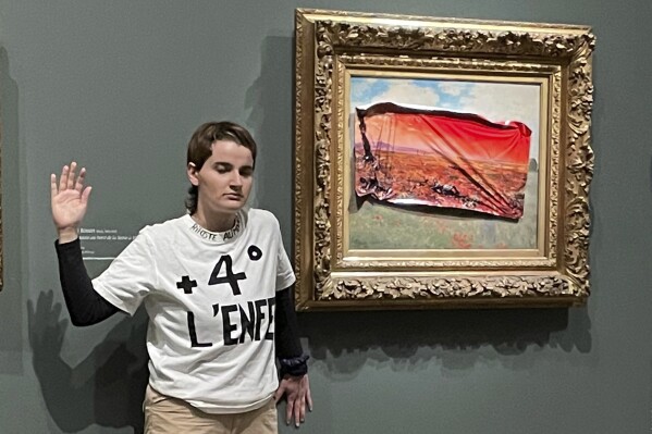 This photo provided by Riposte Alimentaire shows an environmental activist posing by "Poppy Field'' by Claude Monet at the Orsay museum, Saturday, June 1, 2024 in Paris. The activist was detained after sticking a protest sign on a Monet painting, calling for action to protect food supplies from further damage to the climate. (Riposte Alimentaire via AP)