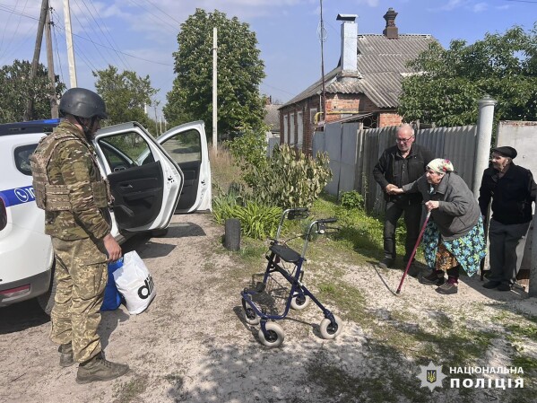 In this photo provided by the Ukrainian Police, police evacuate elderly people following the Russian attack around the town of Vovchansk in Kharkiv region, Ukraine, Friday, May 10, 2024. (Ukrainian Police via AP)