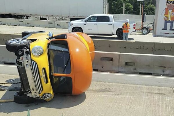 In this photo provided by Chicago Critter, one of Oscar Mayer’s hot dog-shaped Wienermobiles is flipped onto its side after crashing along Interstate 294, a suburban Chicago highway, Monday, July 22, 2024, in Oak Brook, Ill. (Chicago Critter via AP)