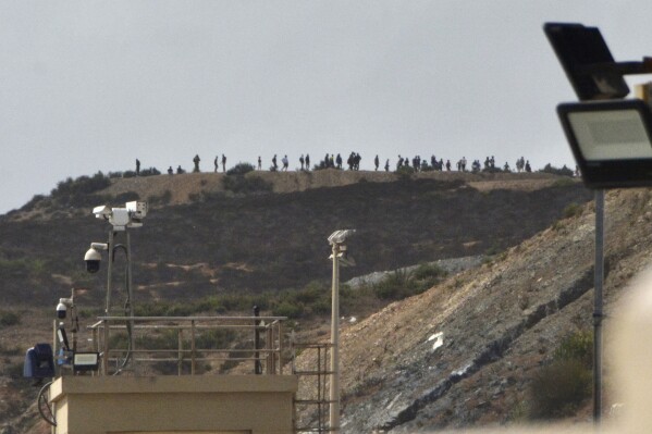 People thought to be migrants stand on top of hill at the Tarajal border in the Spanish enclave of Ceuta, Sunday, Sept. 15, 2024. (Antonio Sempera/Europa Press via AP)