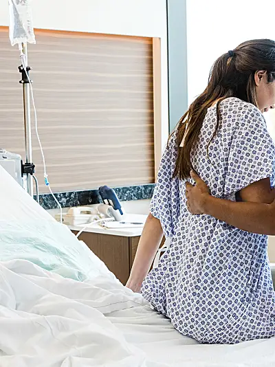 Nurse assisting woman sitting up in hospital bed