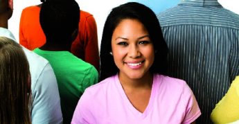 Female wearing a pink tshirt smiling in a crowd.