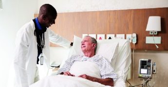 Doctor Visiting And Talking With Senior Male Patient In Hospital Bed