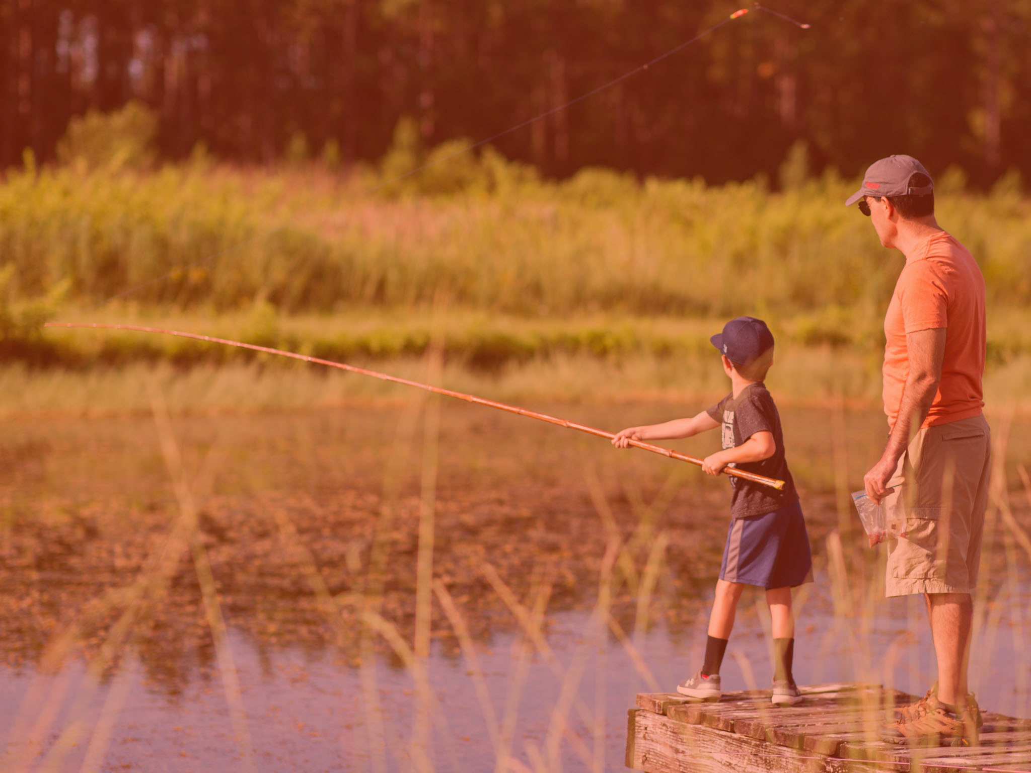 Two people fishing at the Fishing for Success Extension program. Orange overlay.