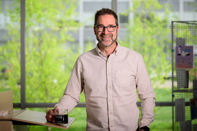 Psychology professor Brent Roberts stands in front of a large window with trees outside.