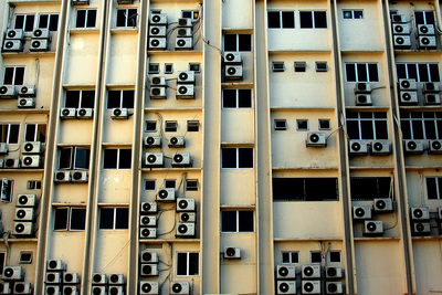 This image shows air conditioner units in windows of an urban highrise building.