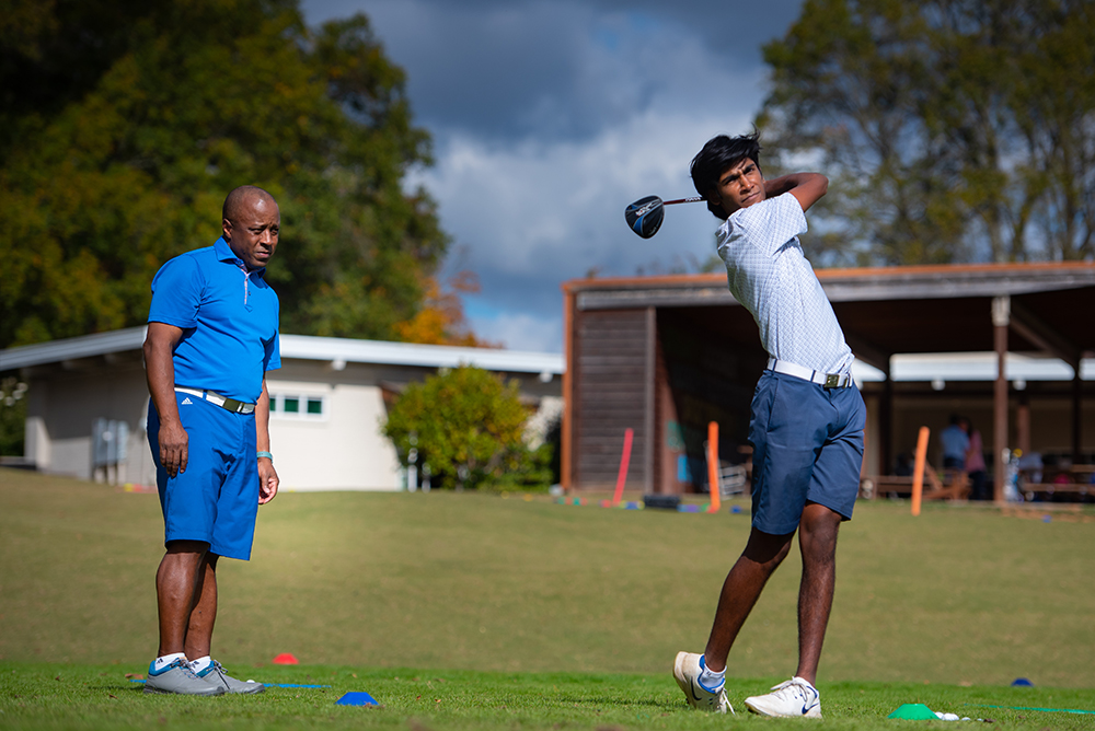 First Tee mentor watches participant on golf course.