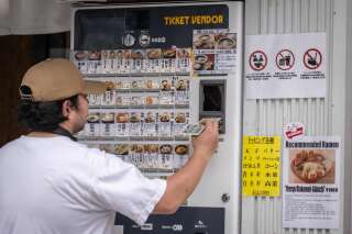 Un client glisse un billet de 1 000 yens dans un distributeur de tickets installé dans un restaurant, à Tokyo, le 17 juin 2024.