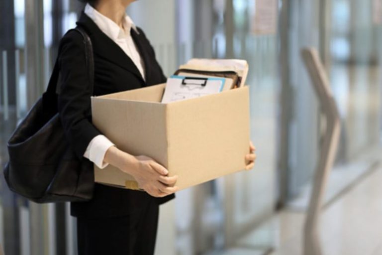 Mulher em um ambiente corporativo segurando uma caixa com pertences pessoais. Imagem: Getty Images