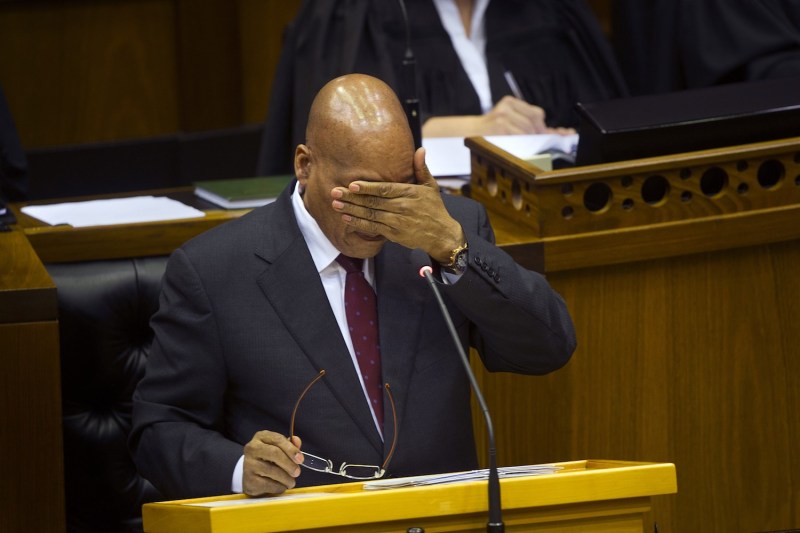 South African President Jacob Zuma wipes his face with his hand as he answers hostile questions at the South African parliament in Cape Town on August 6, 2015.