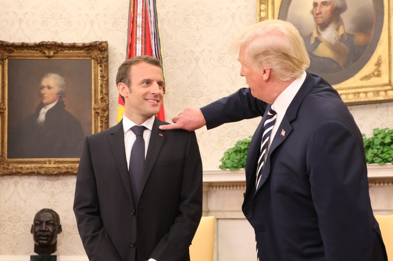 U.S. President Donald Trump, right, clears dandruff off French President Emmanuel Macron's jacket in the White House Oval Office in Washington on April 24. (Ludovic Marin/AFP/Getty Images)