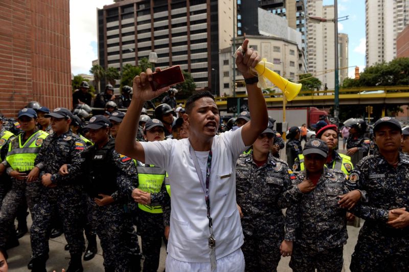 A health worker shouts slogans demanding fair and higher wages during a protest of the lack of medical supplies and poor conditions in hospitals, in front of a line of police  in Caracas on Aug. 16. (Federico Parra/AFP/Getty Images)
