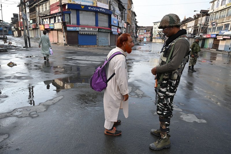 An Indian soldier questions a man on a street during a curfew in Srinagar on August 8, 2019.