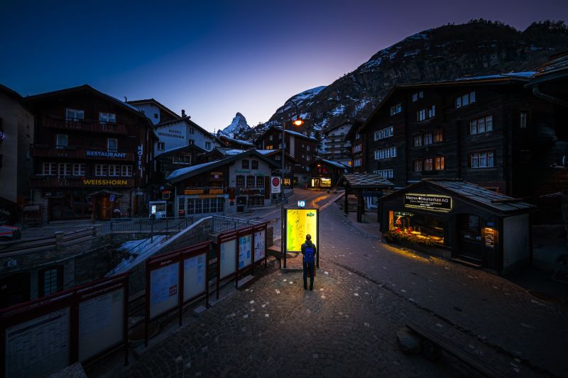 A pedestrian looks at an illuminated map board in the empty streets of the Alpine resort of Zermatt, with the Matterhorn mountain amid the spread of the COVID-19 caused by the novel coronavirus.