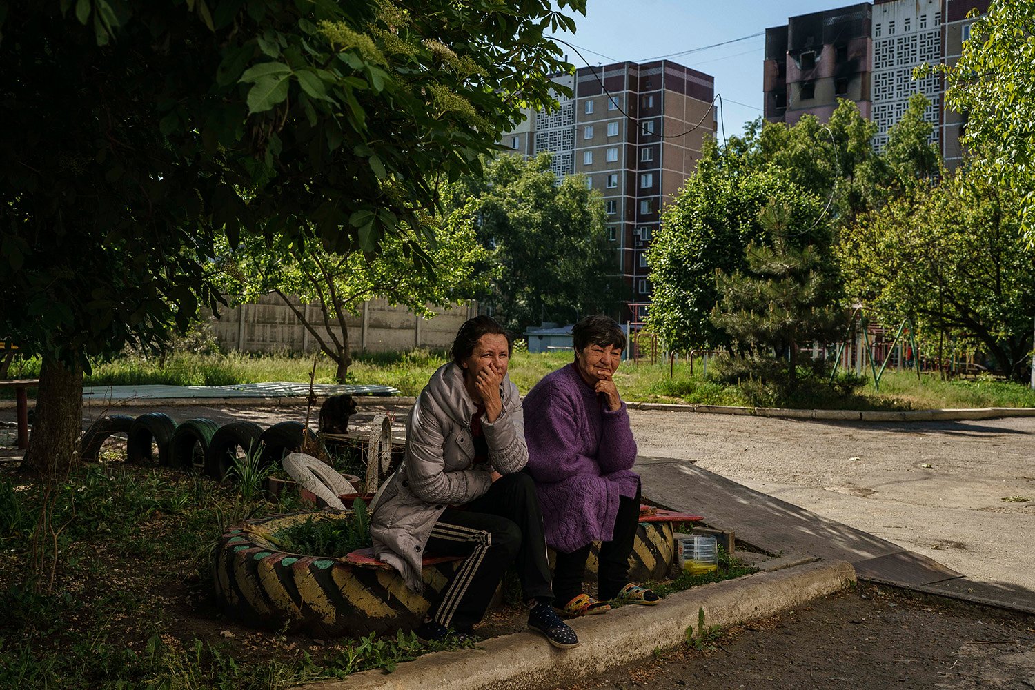 Two women rest in the shade in front of a burned out residential block on May 25.