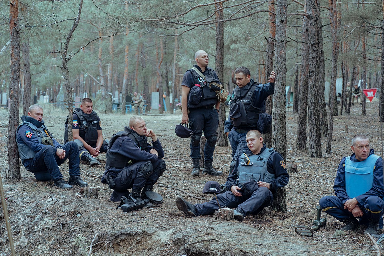 Ukrainian police officers rest during work to exhume bodies at a mass burial site in Izyum, Ukraine.