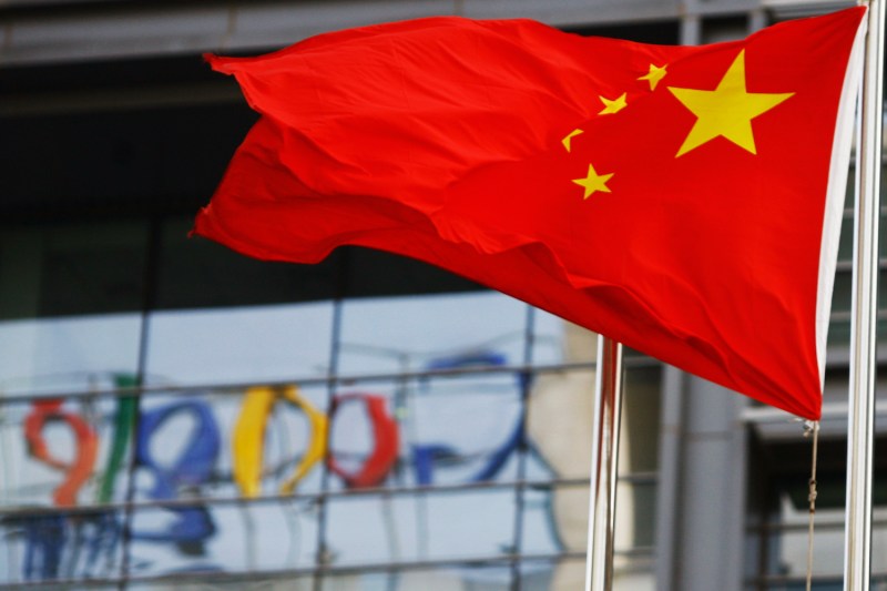The Google logo is reflected in windows of the company's China head office as the Chinese flag flies in the wind in Beijing.