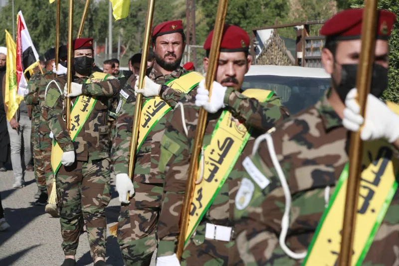 Fighters carry flags of Iraq and paramilitary groups, including Kataib Hezbollah.