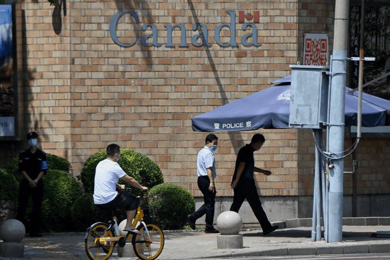 People walk past the Canadian Embassy in Beijing on Aug. 10, 2021.