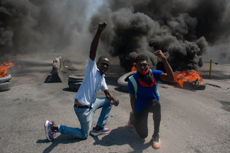 Protesters react as tires burn in the street during a demonstration following the resignation announcement of acting Haitian Prime Minister Ariel Henry, in Port-au-Prince, Haiti, on March 12.