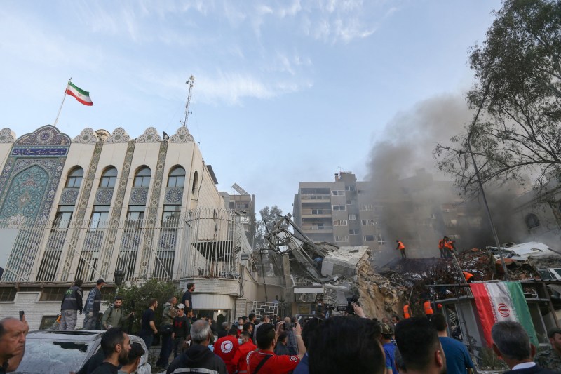 Emergency and security personnel search rubble following an airstrike that hit a building next to the Iranian Embassy.