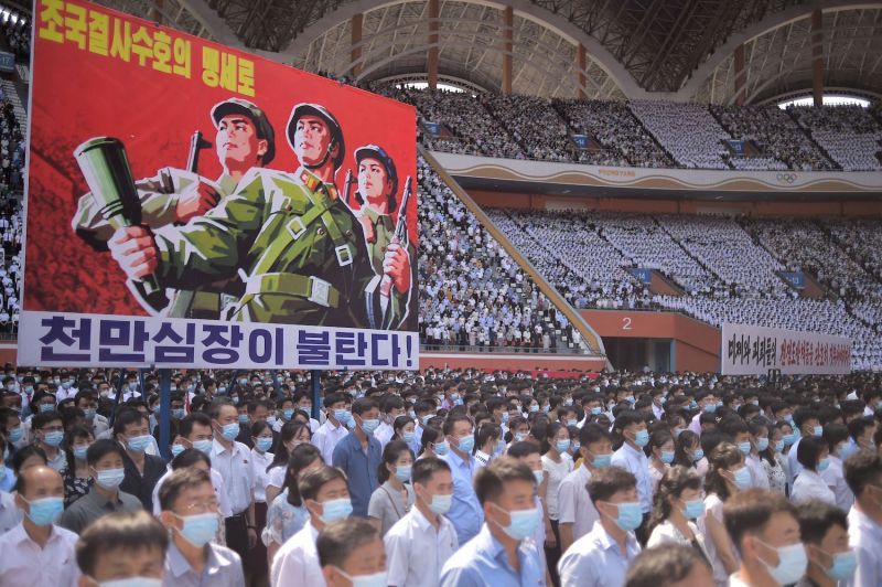 North Koreans stand next to a banner that reads “Tens of millions of people pledge to defy death for defending country!” as they attend a mass rally to mark the “Day of Struggle Against U.S. imperialism” in Pyongyang on June 25, 2023.
