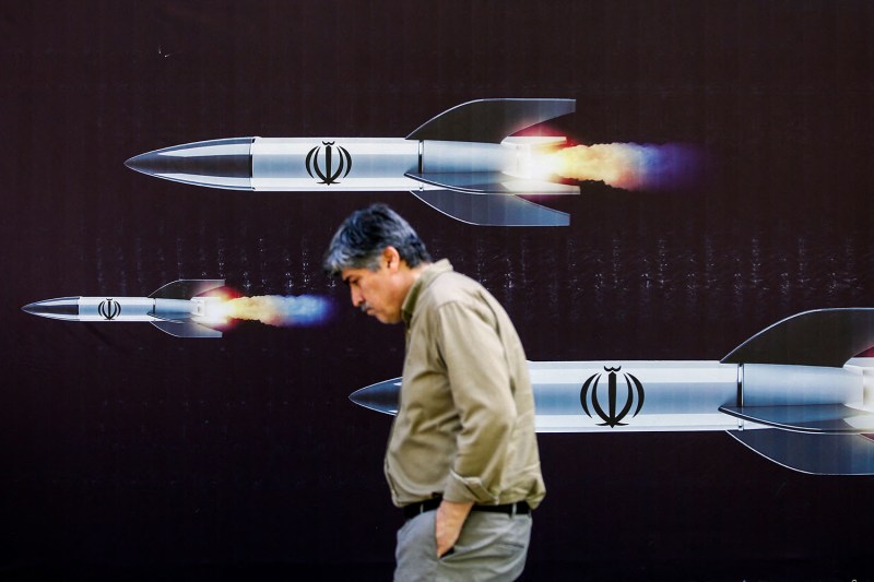 A man walks past a banner depicting Iranian missiles along a street in Tehran on April 19.