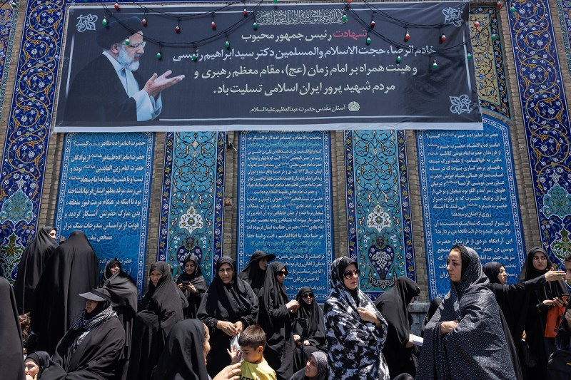 A banner depicting the late President Ebrahim Raisi hangs above a gathering of women at the Shah Abdol-Azim shrine in Rey, a conservative southern suburb of Tehran, during the funeral of Foreign Minister Hossein Amir-Abdollahian.