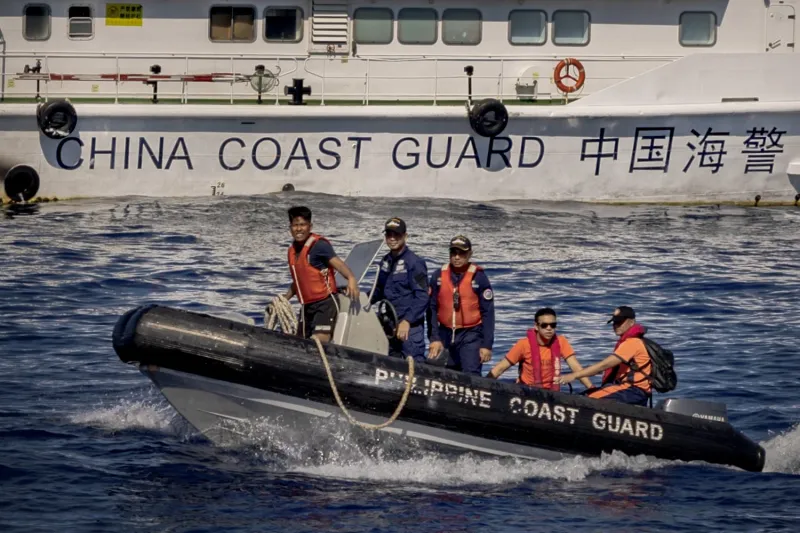 Philippine Coast Guard members pass a China Coast Guard vessel during a resupply mission to Second Thomas Shoal in the South China Sea on March 5.