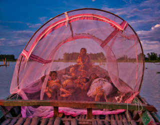 Shahidul Islam et Rowshan Ara, avec leurs deux filles Sayma Khatun et Sumaiya Khatun sous une moustiquaire sur leur bateau. Photo : PAM/Sayed Asif Mahmud