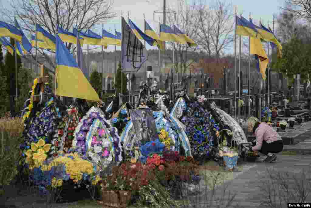 A woman tends to the grave of a fallen soldier relative in the Bucha cemetery, near Kyiv, in March 2024.&nbsp;