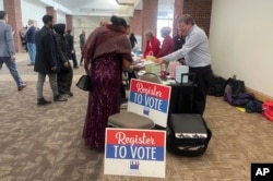 FILE - People approach a table where they can register to vote after becoming U.S. citizens during a naturalization ceremony at a convention center in St. Paul, Minn., March 9, 2023. (AP Photo/Trisha Ahmed)